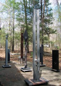 several tall metal sculptures in the woods