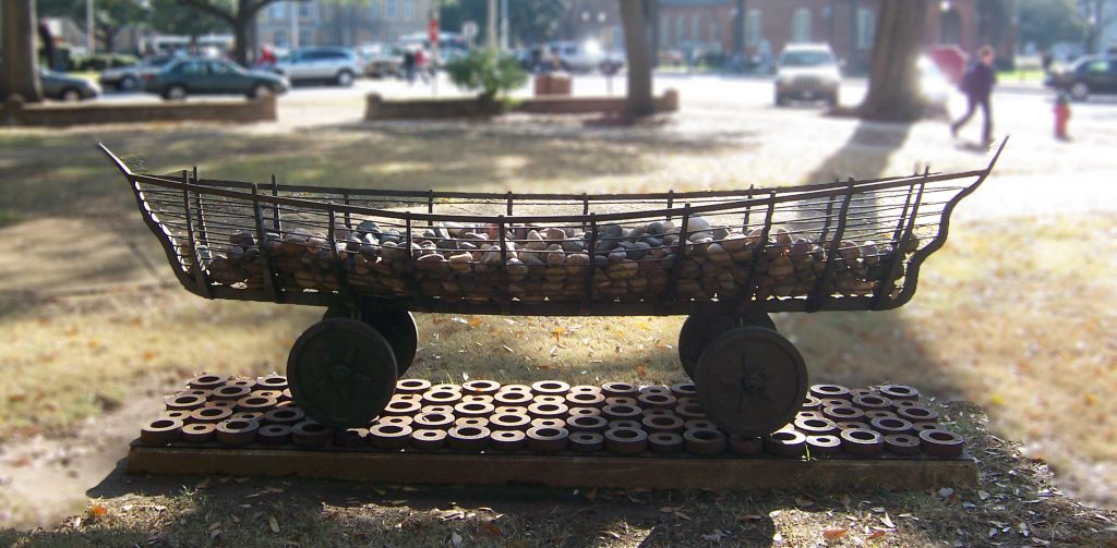 a sculpture resembling a canoe on wheels, filled with rocks