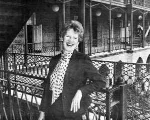 a woman posing on the second floor railing of Woods Hall