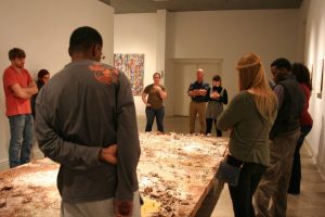 Class critiquiing work by Heather Leigh Whidden; painting by Joshua Whidden in background, in Bilateral; Memory & Experience, 2015, Sella-Granata Art Gallery. 
