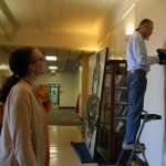 Emily Bibb and Bill Dooley measure the space and prepare to hang the larger than life size painting in the foyer of Morgan Hall.