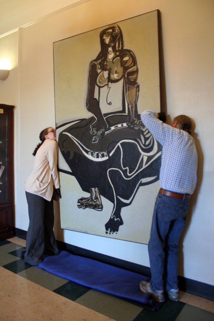 Emily Bibb and Bill Dooley hang "Cassandra" by Ben Smith in the foyer of Morgan Hall.