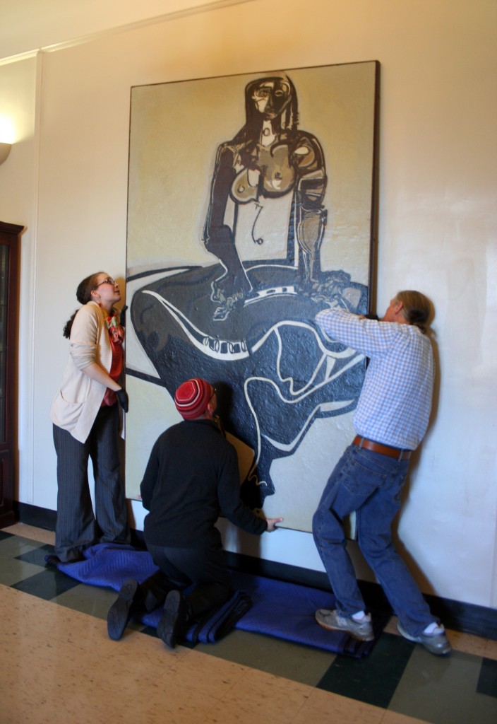 Emily Bibb and Bill Dooley get assistance from Joel Brouwer in hanging "Cassandra."