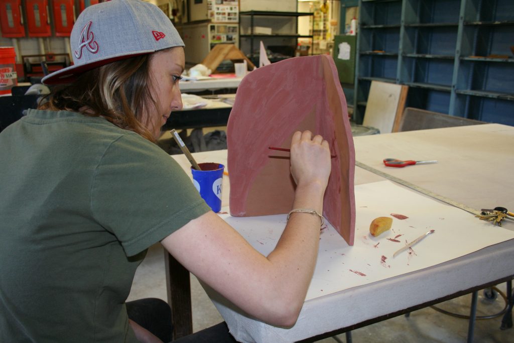 Grad student Sydney Ewerth paints a ceramic piece that will be part of a sculptural installation by artist Amy Pleasant.