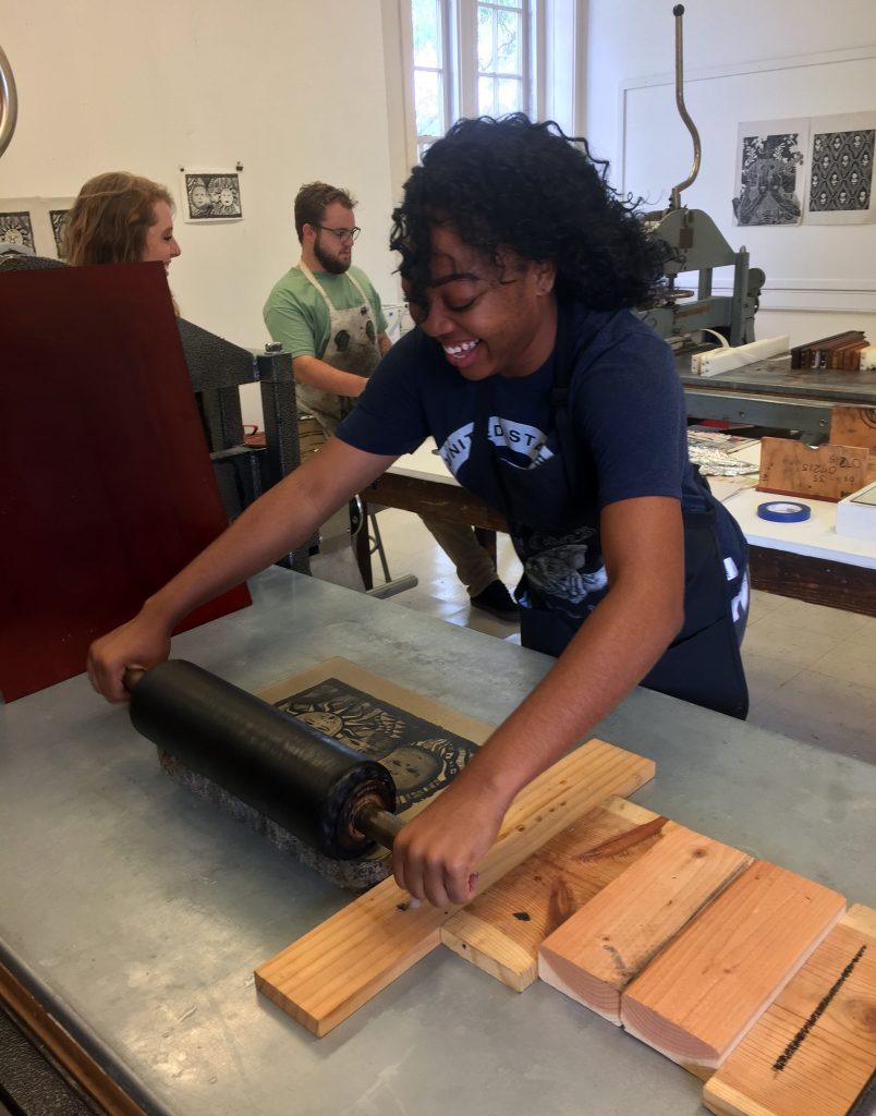 a student rolls up her stone in the litho shop.