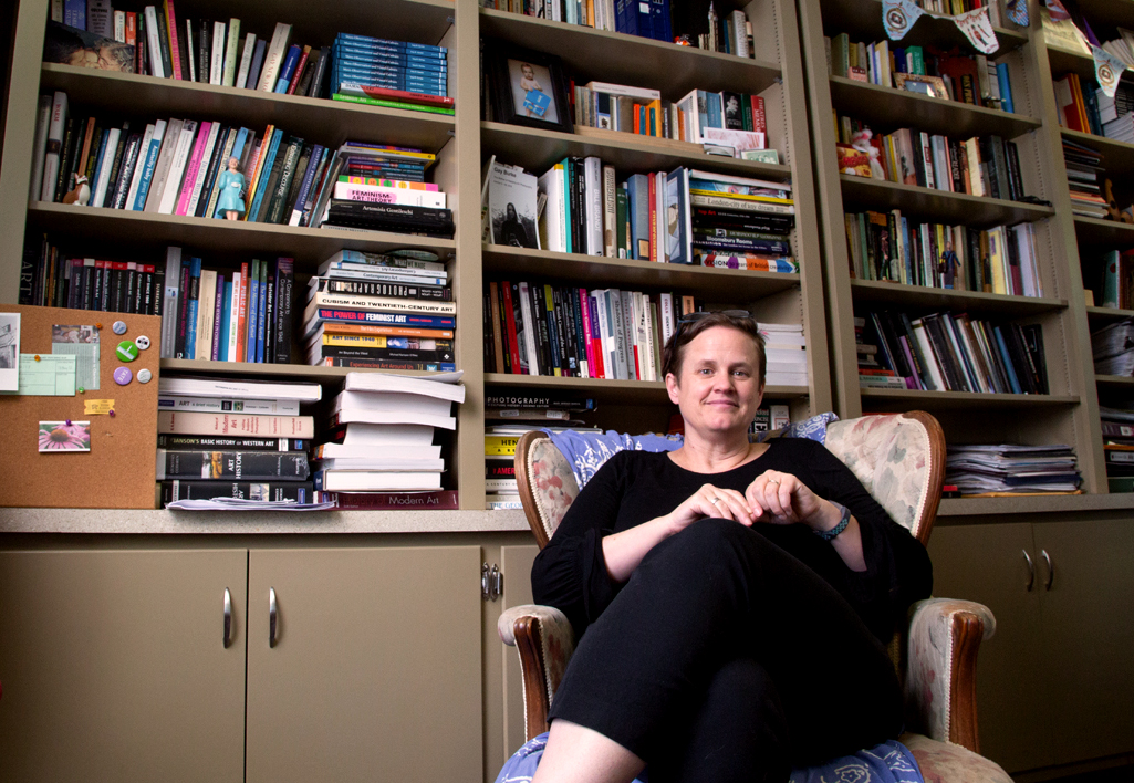 a faculty member seated in front of full bookshelves