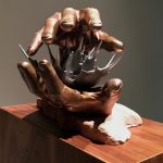 bronze sculpture of two hands around spiked flower