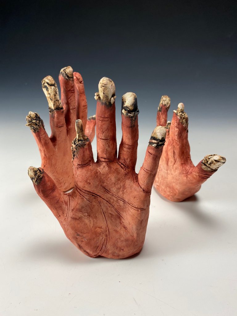 three ceramic hands reaching upward by Sandra Vega