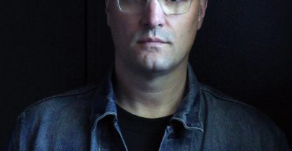 head and shoulders of a white male, mid-to-late 30s, in a denim jacket, mostly in shadow