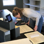 Student leaning over historic archival papers at the Thomas
