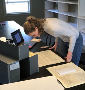 Student leaning over historic archival papers at the Thomas